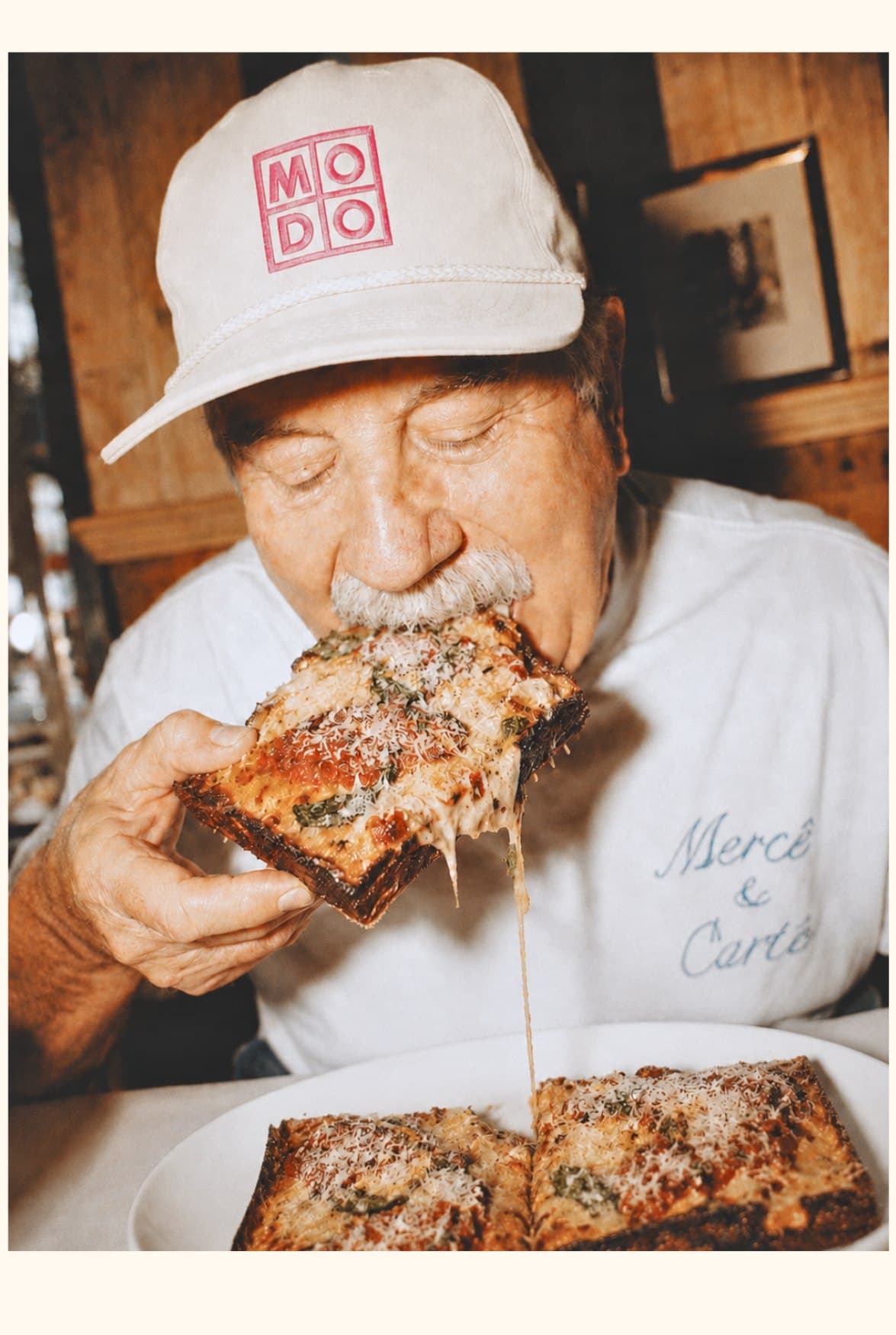 Tony, founder and head chef of MODO, eating a square Detroit-style pizza slice